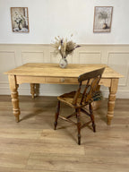 Wooden table with a chair on a wooden floor against a white wall with decorative elements.