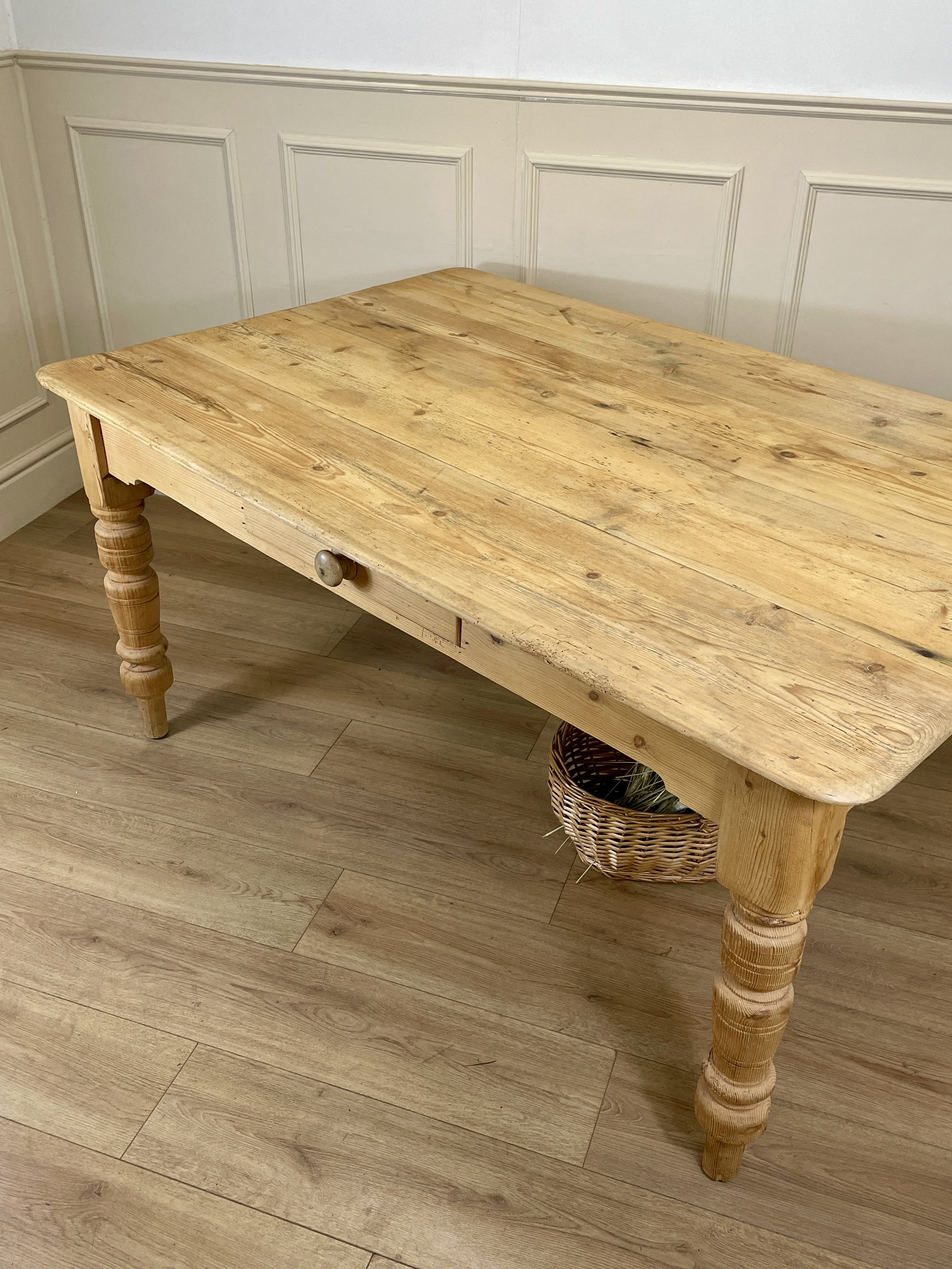 Wooden table with turned legs in a room with panelled walls and wooden flooring.