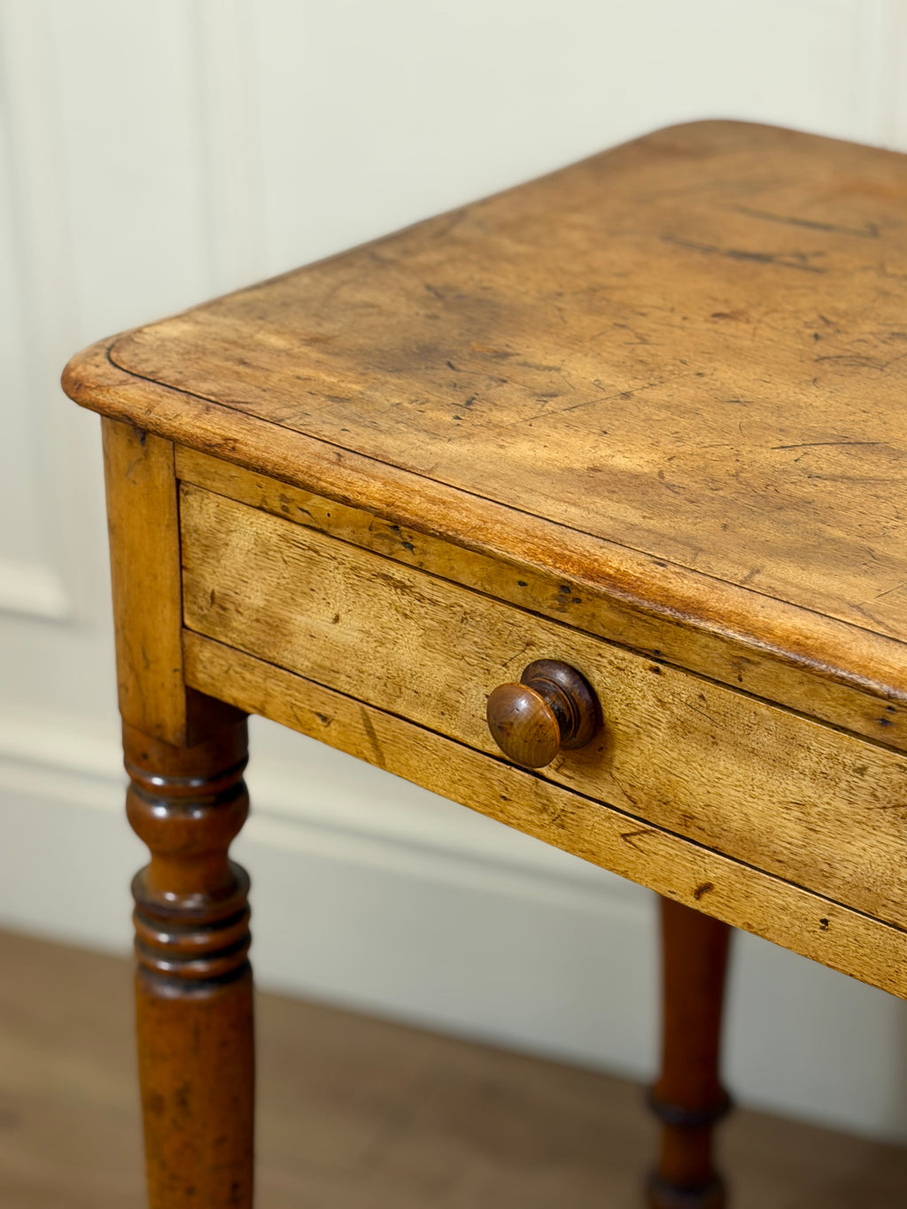 Vintage wooden table with a single drawer against a white wall
