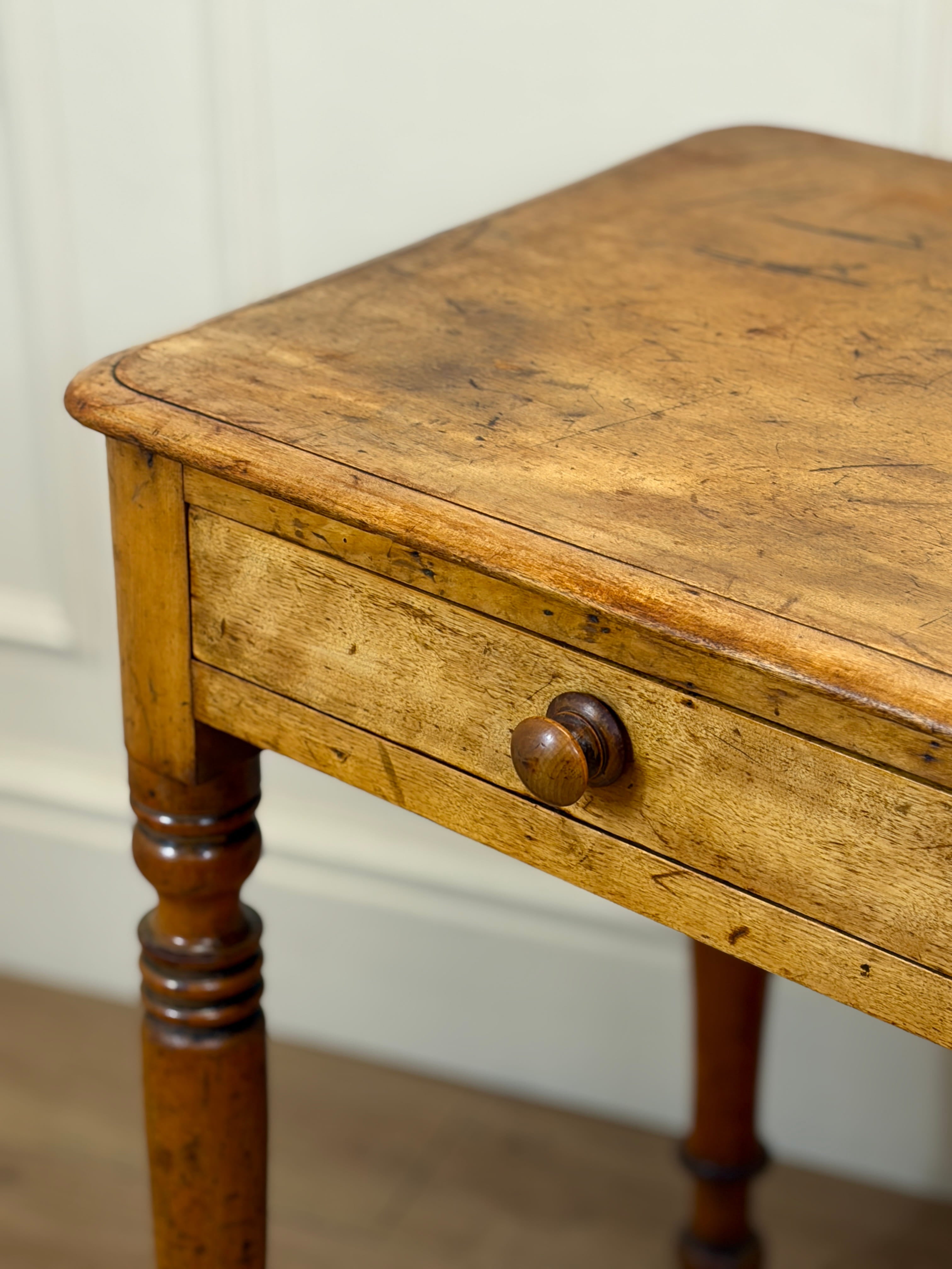 Vintage wooden table with a single drawer against a white wall