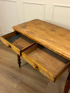 Wooden desk with two drawers in a room with white paneled walls.