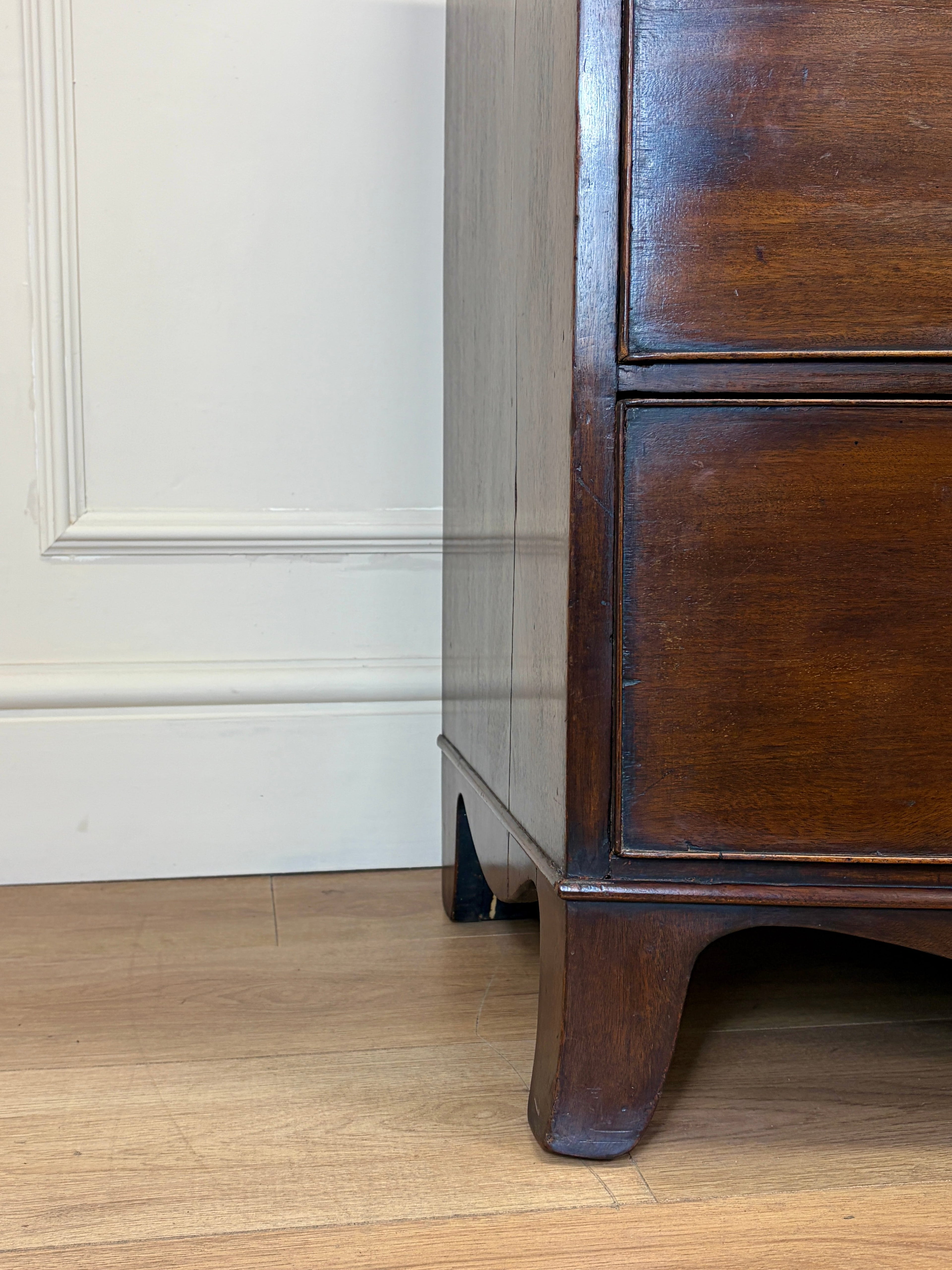 Wooden dresser corner with white wall and wooden floor
