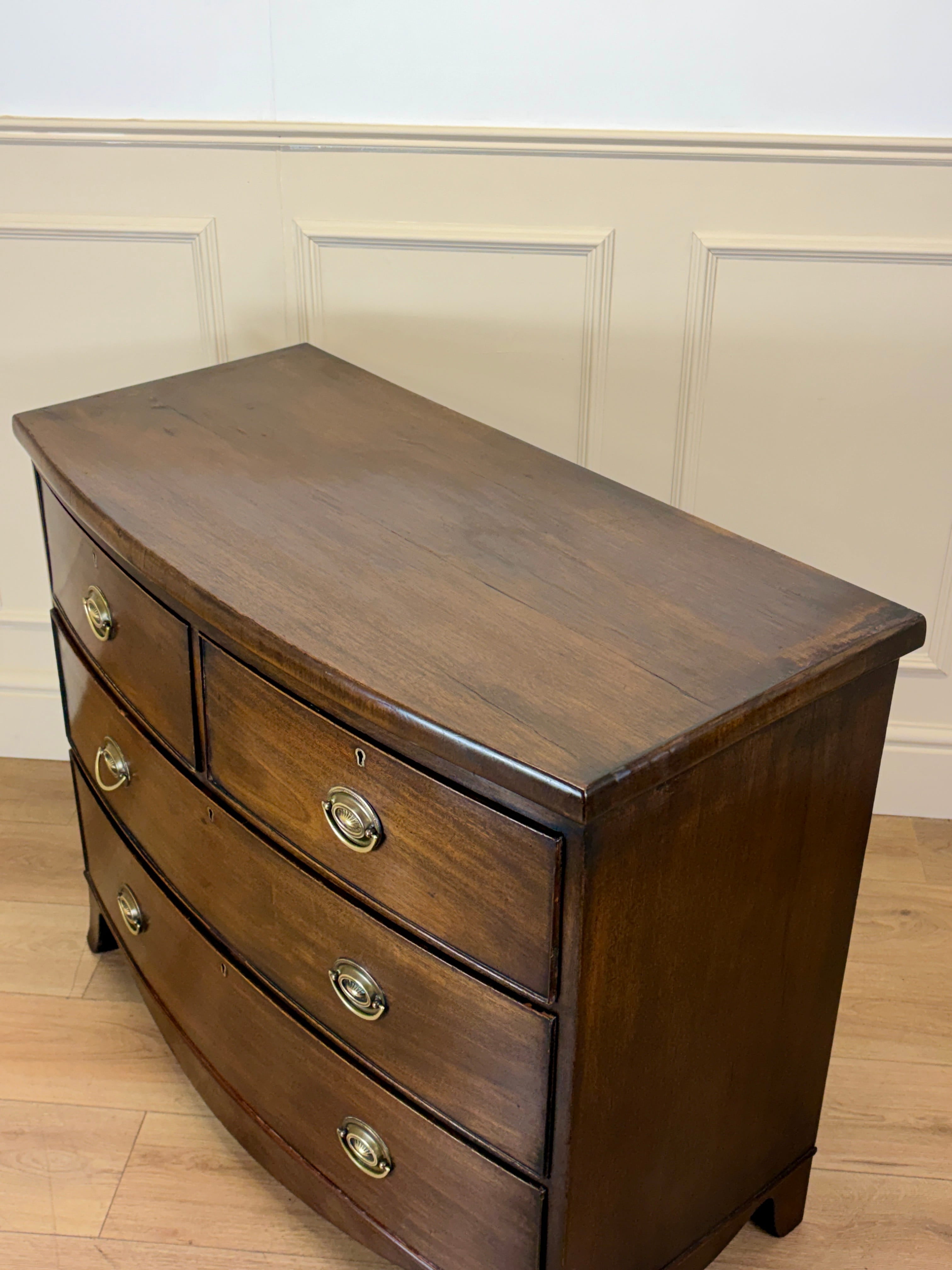 Wooden dresser with four drawers against a white paneled wall.