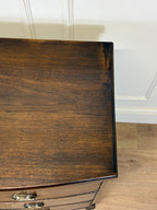 Close-up of a wooden dresser with a white paneled wall in the background