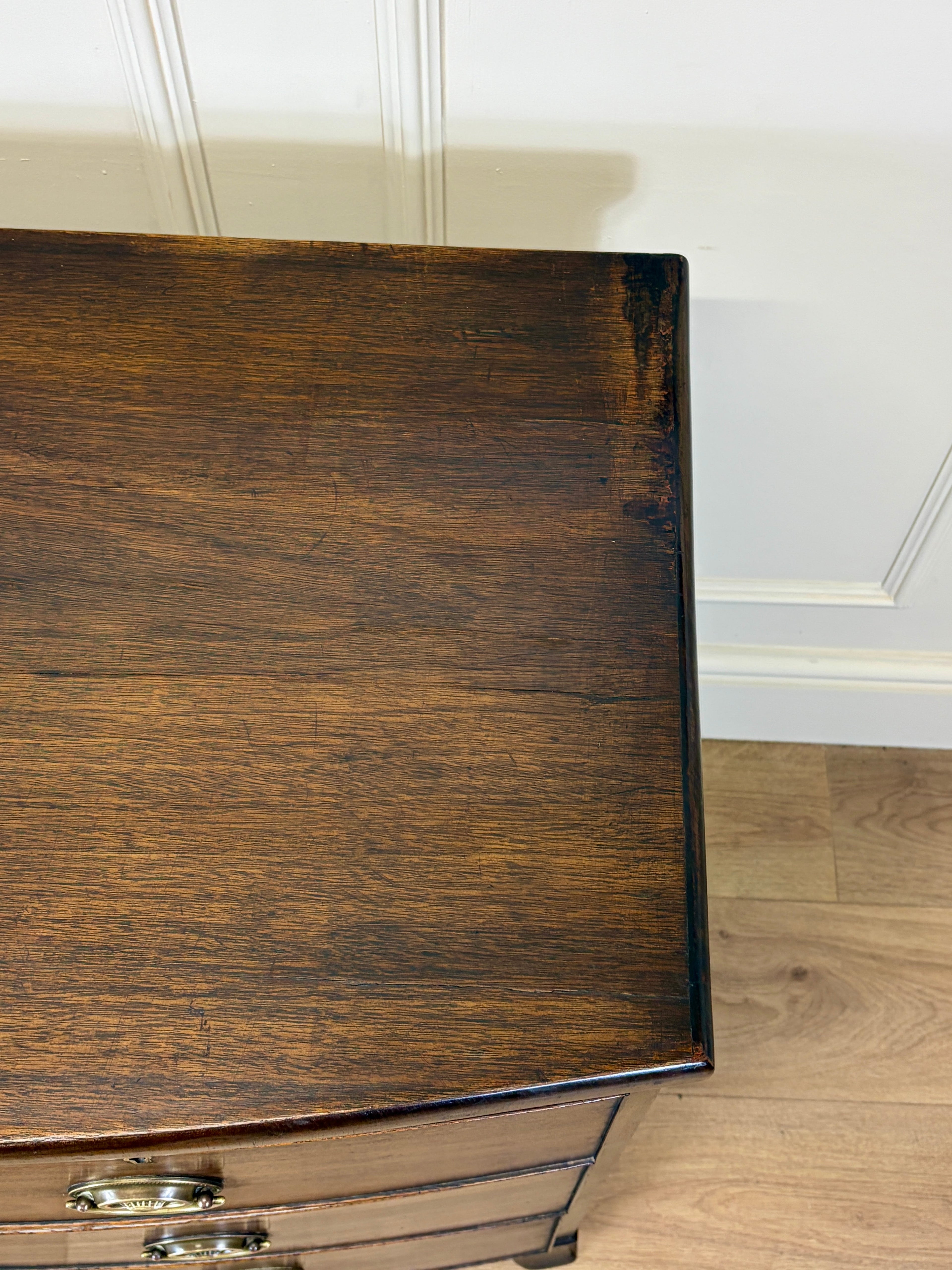 Close-up of a wooden dresser with a white paneled wall in the background