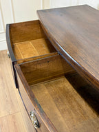 Wooden desk with an open drawer on a wooden floor.