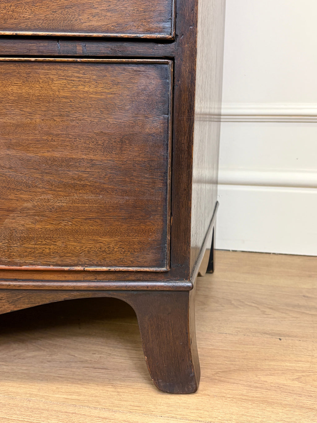 Wooden furniture leg on a wooden floor with a white wall in the background