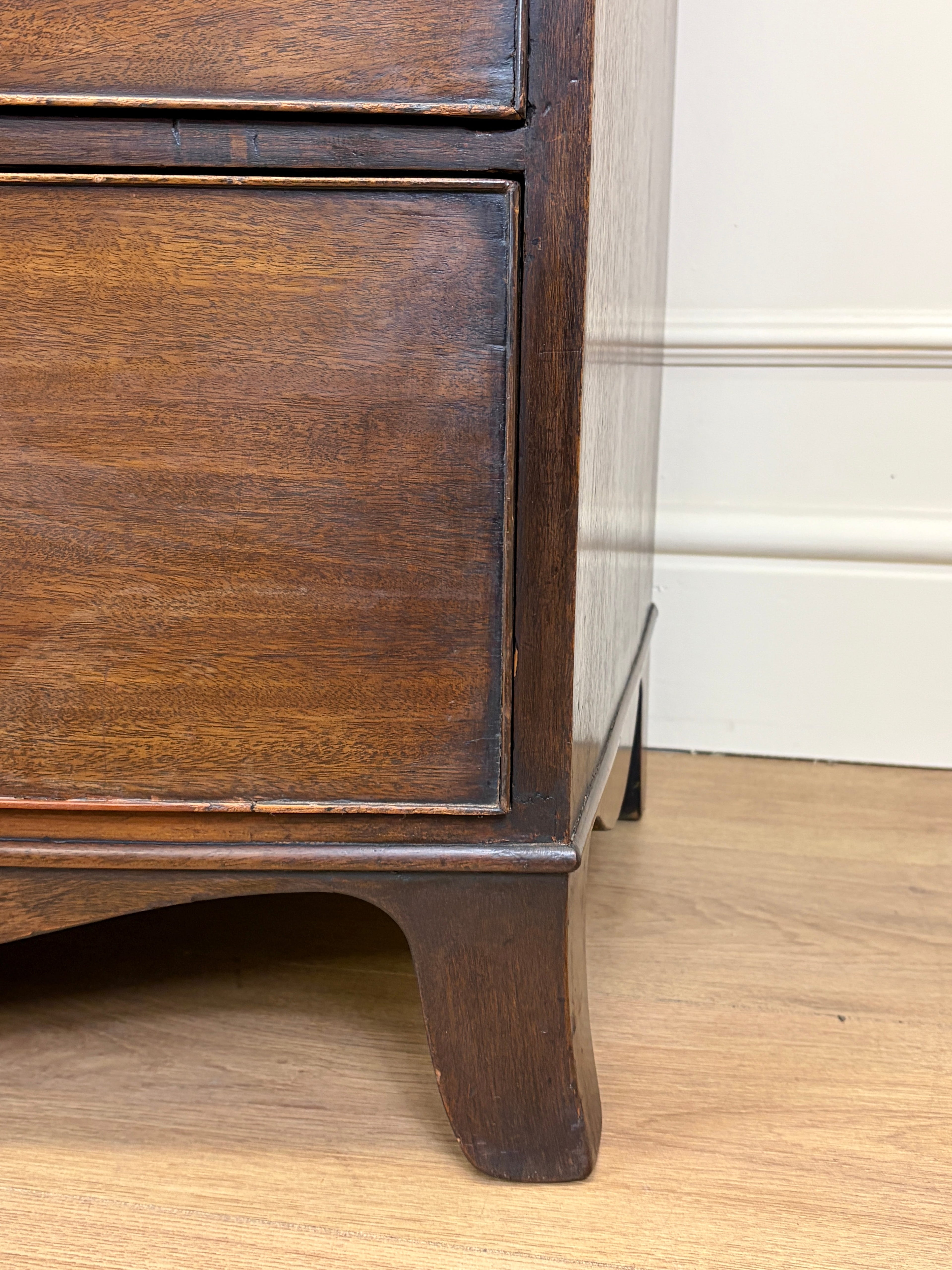 Wooden furniture leg on a wooden floor with a white wall in the background