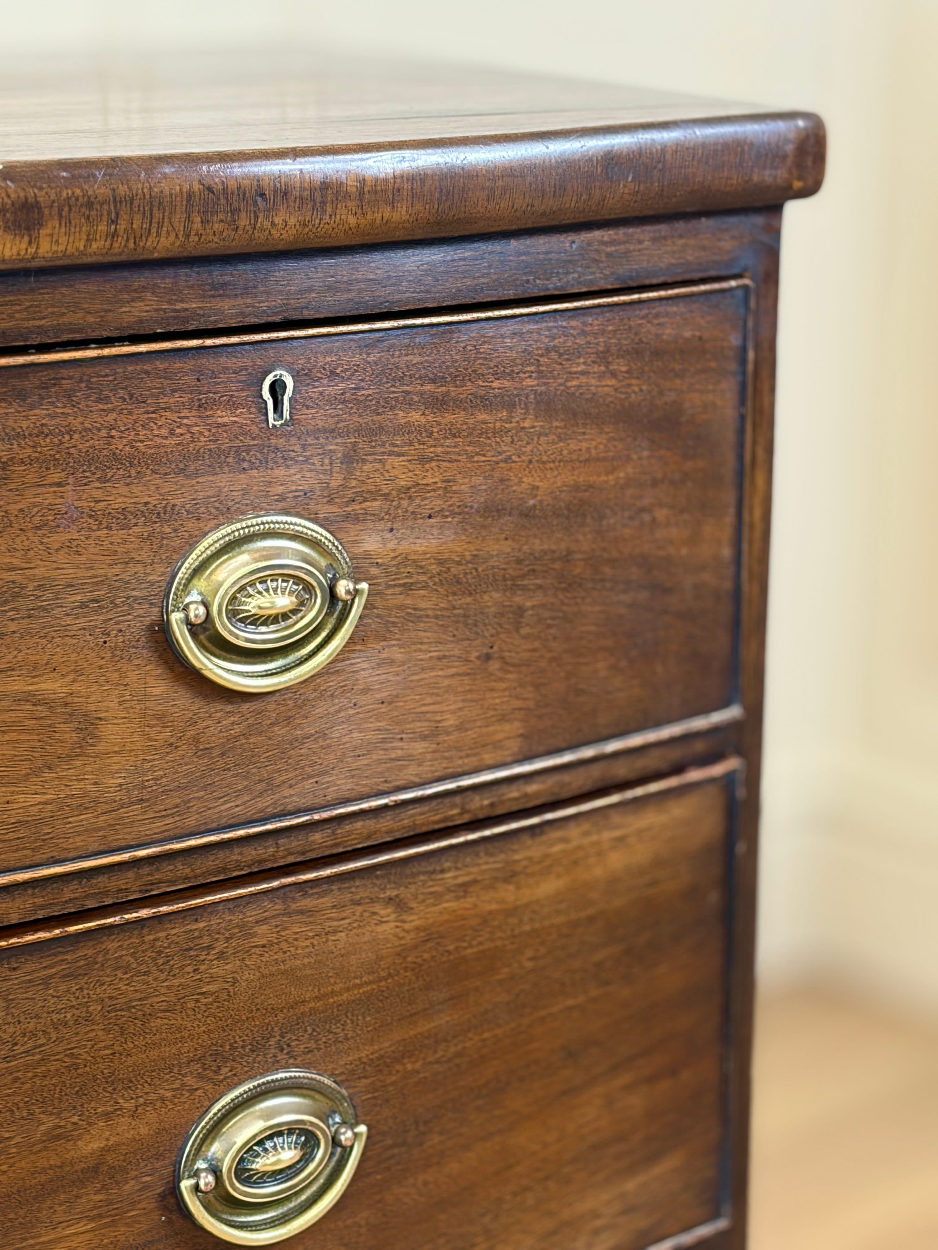 Close-up of a wooden drawer with brass handles on a beige background