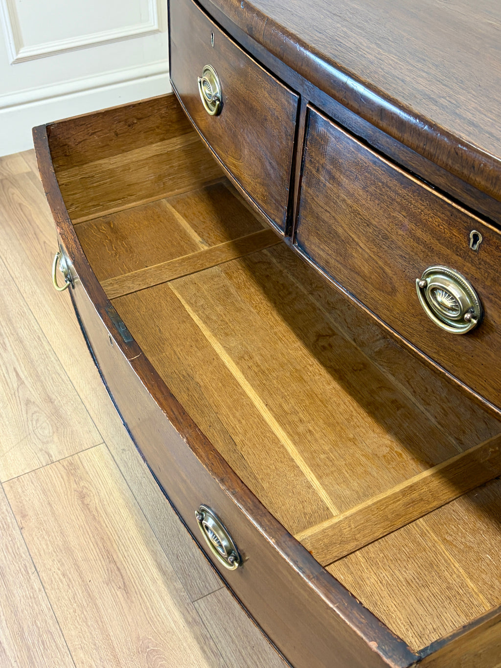 Wooden dresser with open drawer on a light wood floor.
