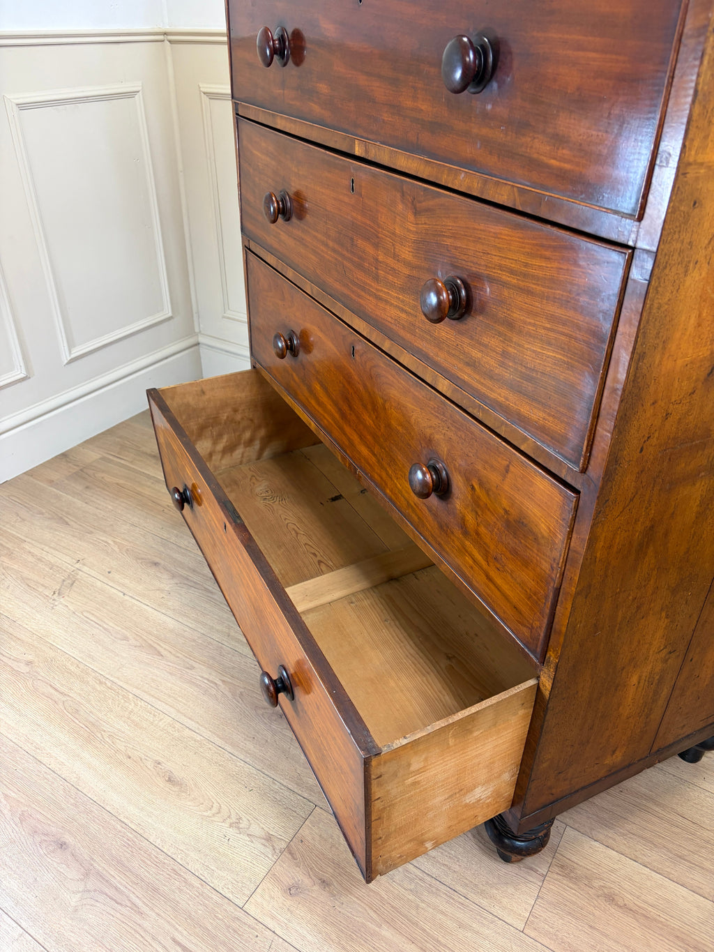 Wooden dresser with open drawer on a wooden floor