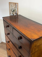 Wooden dresser with a mirror on top against a white wall