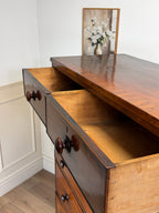 Wooden dresser with open drawer against a white wall