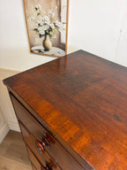 Wooden dresser with a mirror reflecting flowers in the background