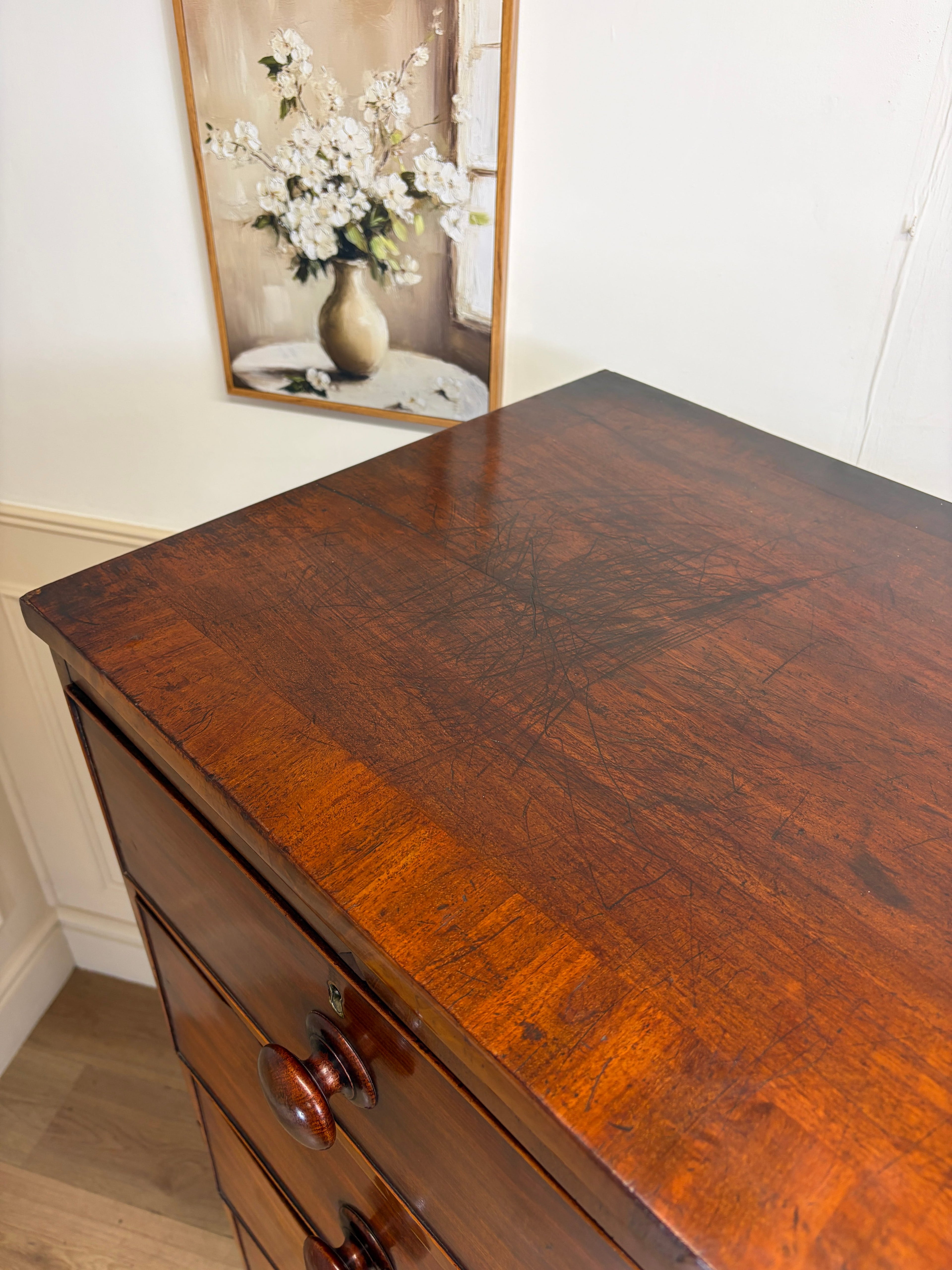 Wooden dresser with a mirror reflecting flowers in the background