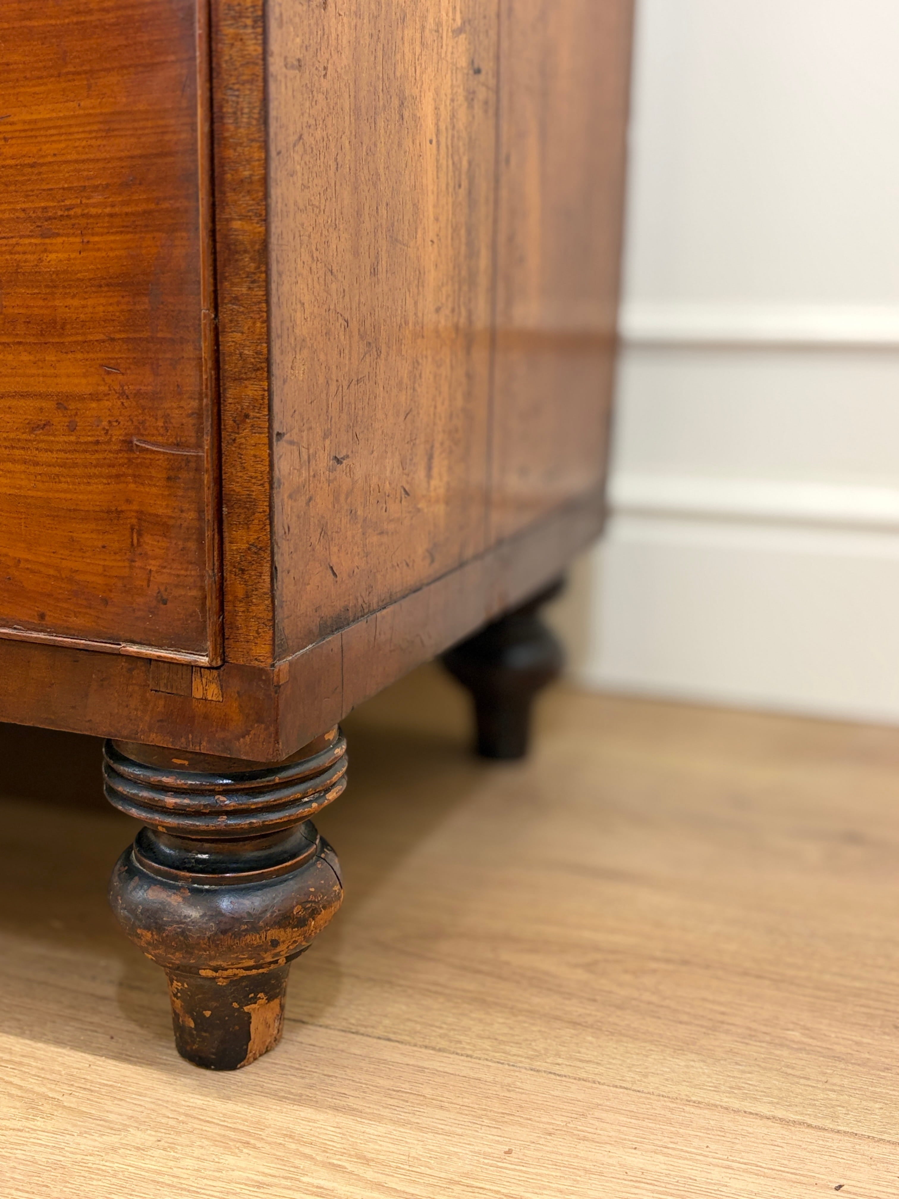 Close-up of a wooden cabinet leg on a wooden floor