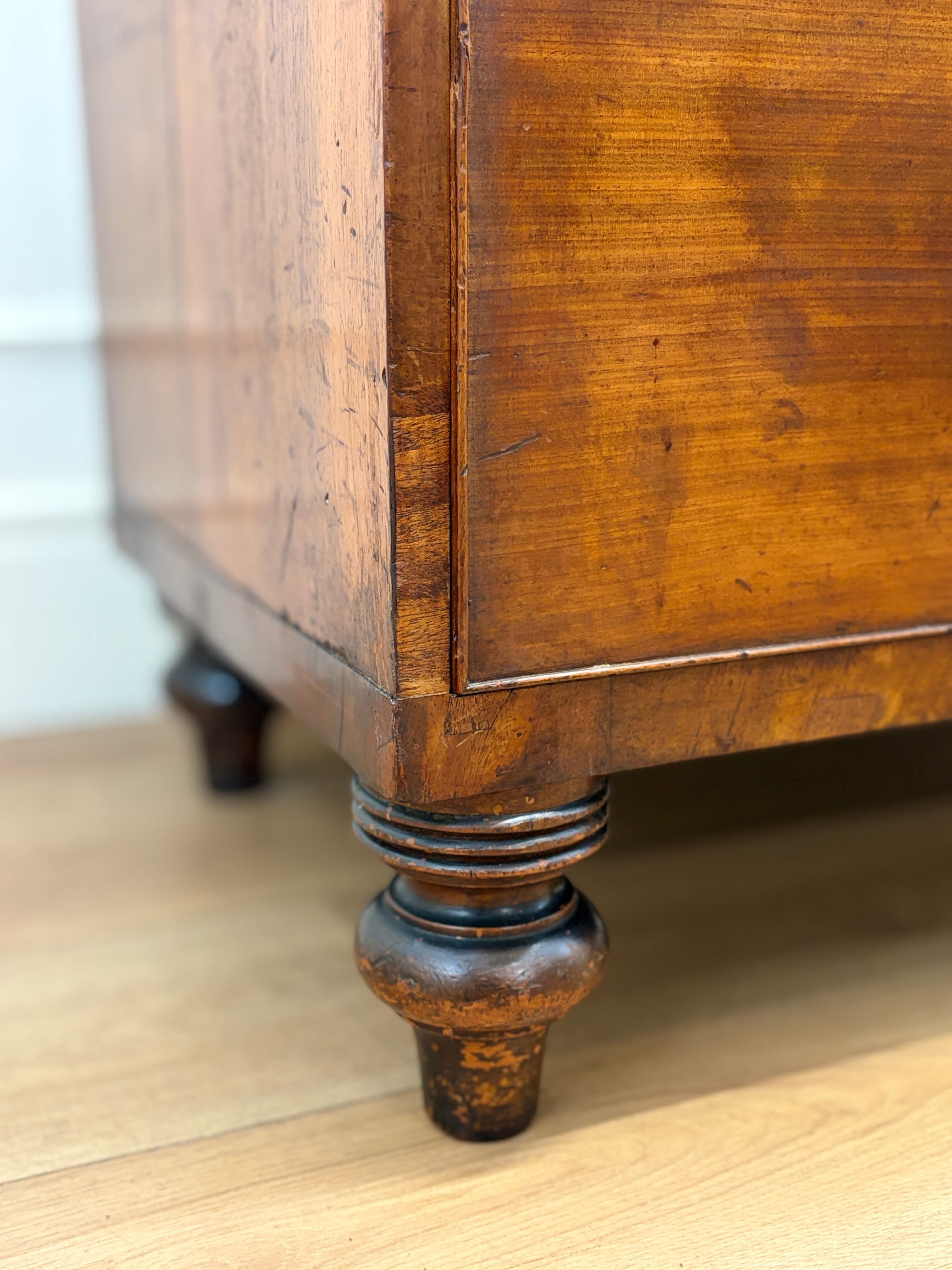 Close-up of a wooden cabinet leg on a light wood floor