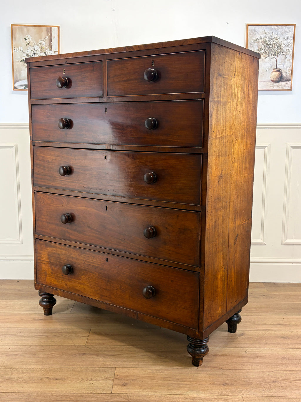Wooden dresser with multiple drawers on a wooden floor.