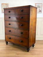 Wooden dresser with multiple drawers on a wooden floor.