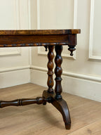 Wooden table with turned legs against a white paneled wall.