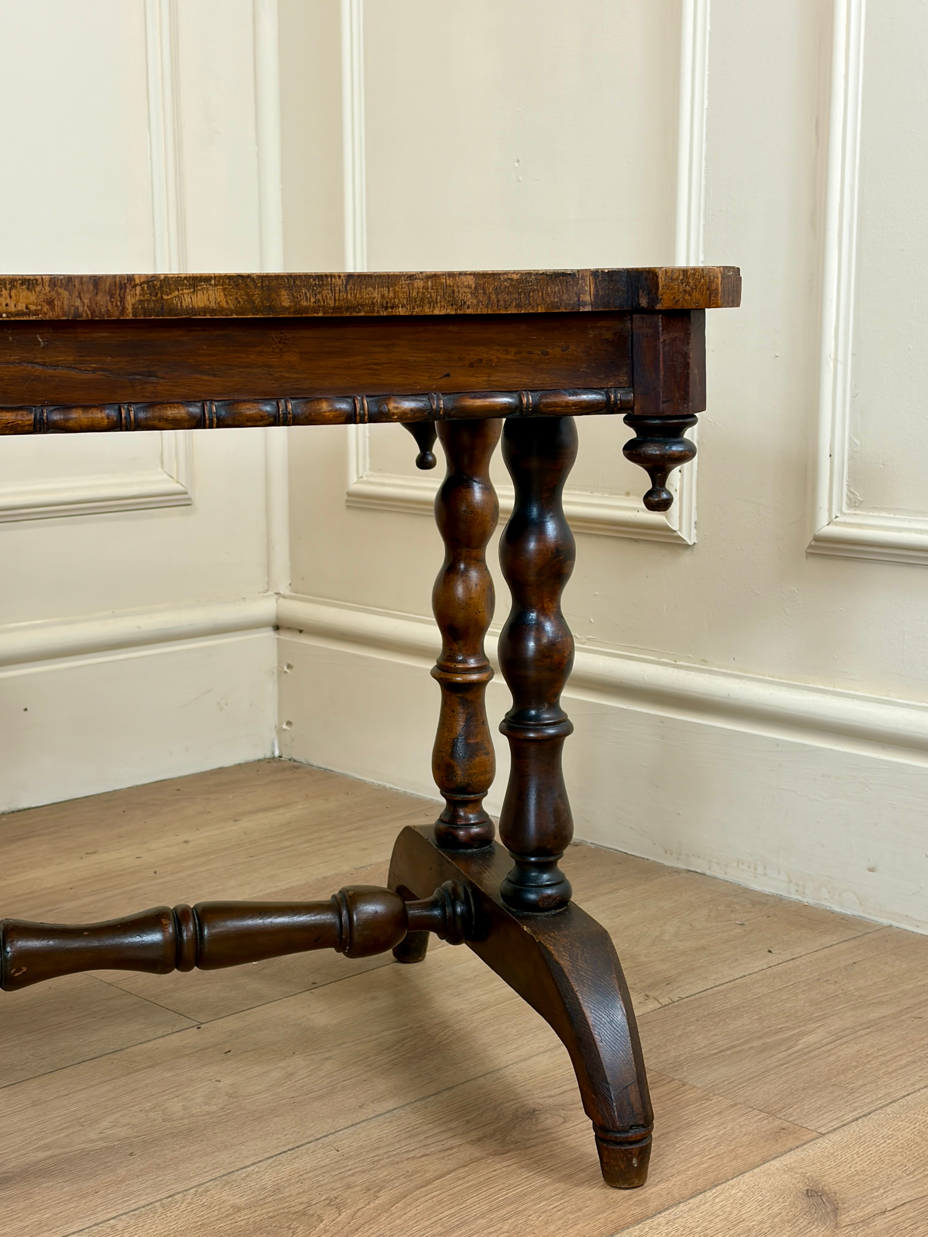 Wooden table with turned legs against a white paneled wall.