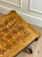 Wooden table with geometric pattern on a light wooden floor.