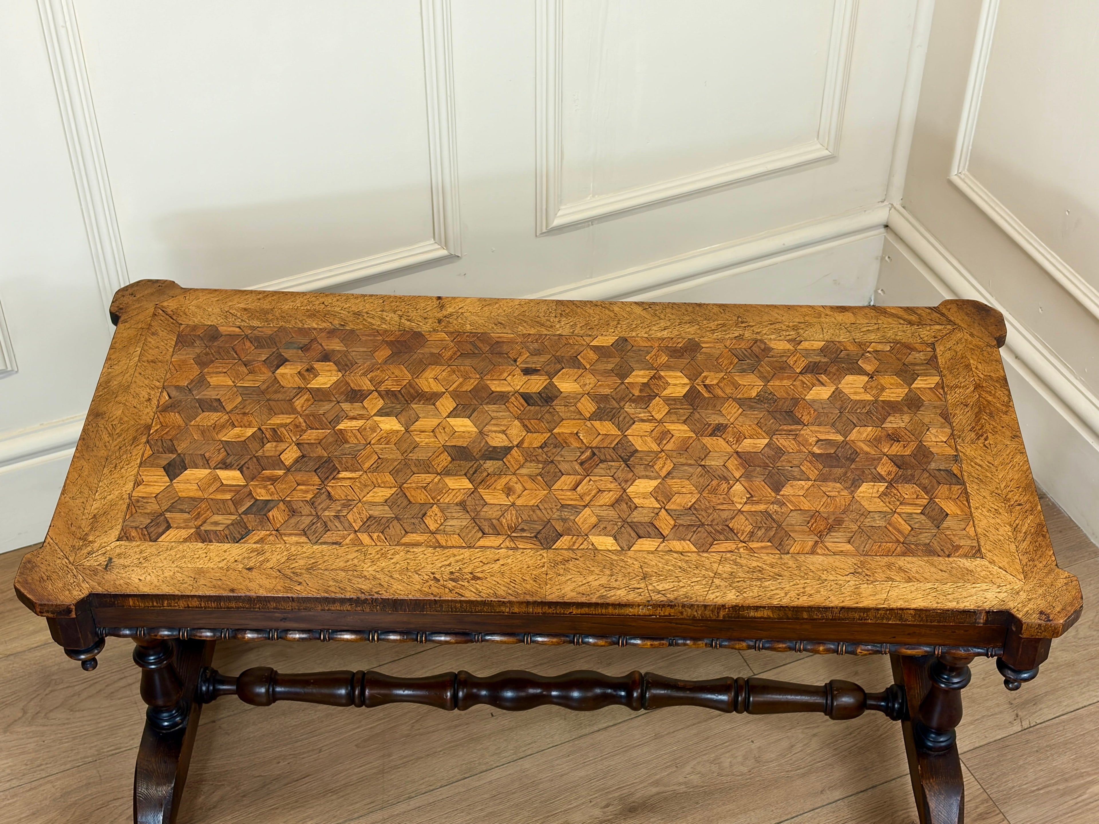 Wooden table with geometric pattern against a white paneled wall