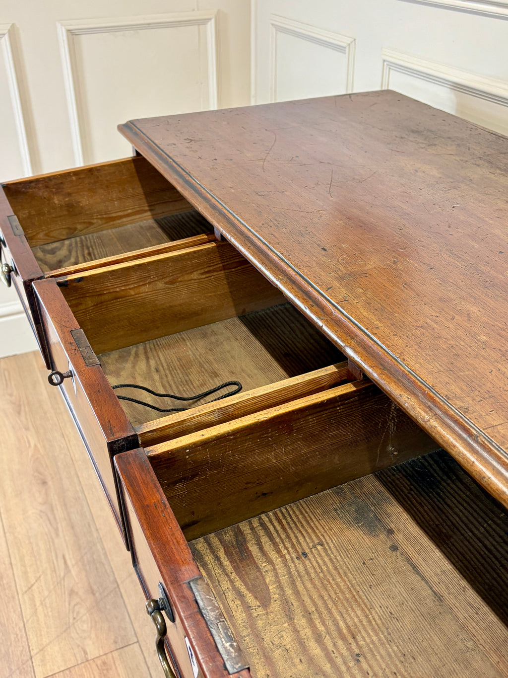 Wooden chest of drawers with a drawer open, revealing a cable inside.