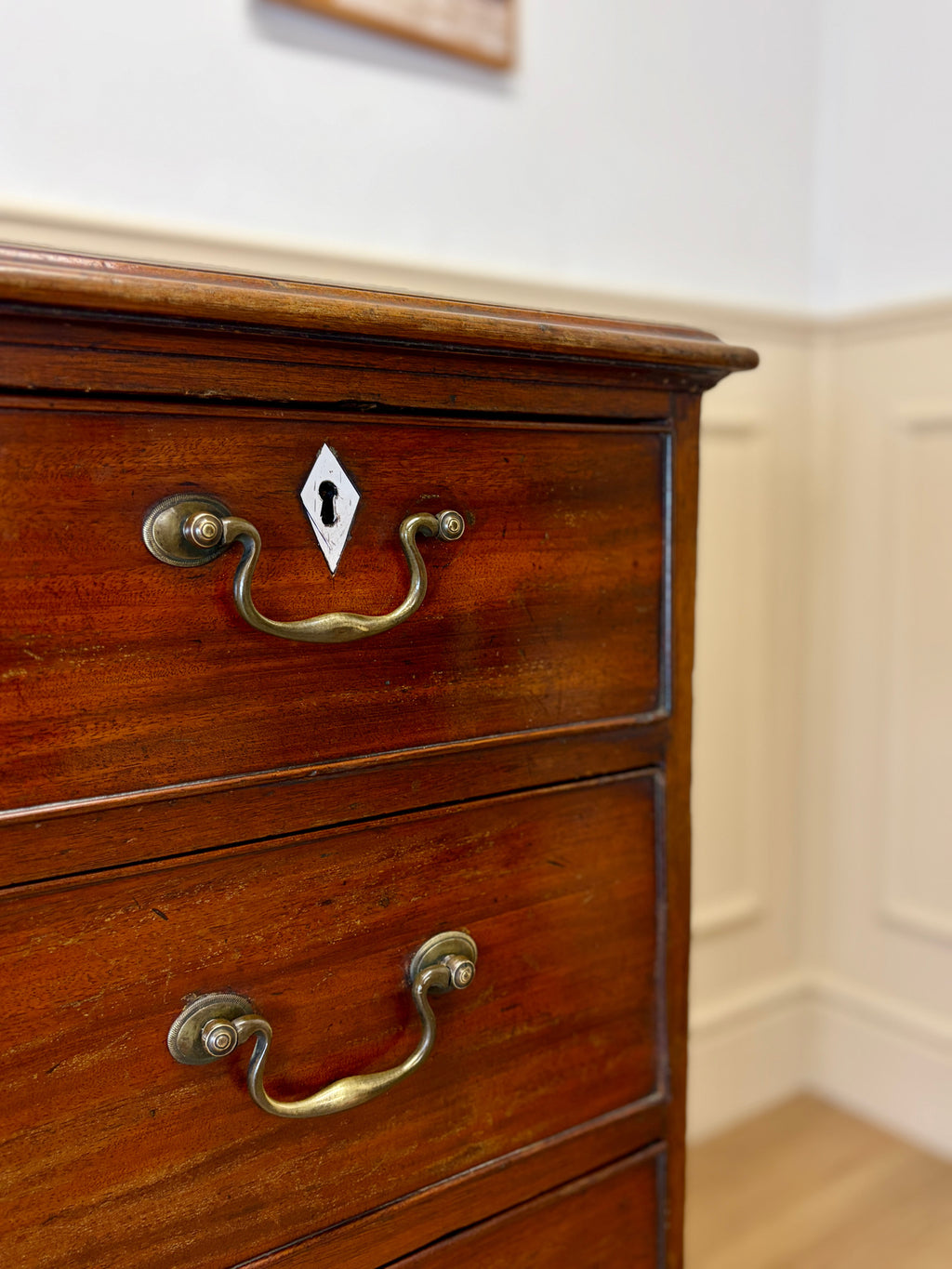 Wooden dresser with brass handles against a neutral wall.