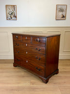 Wooden dresser with multiple drawers in a room with light-colored walls and wooden floor.