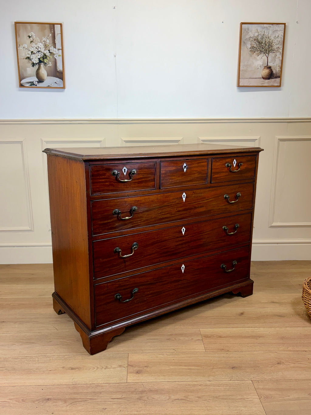 Wooden dresser with multiple drawers in a room with light-colored walls and wooden floor.