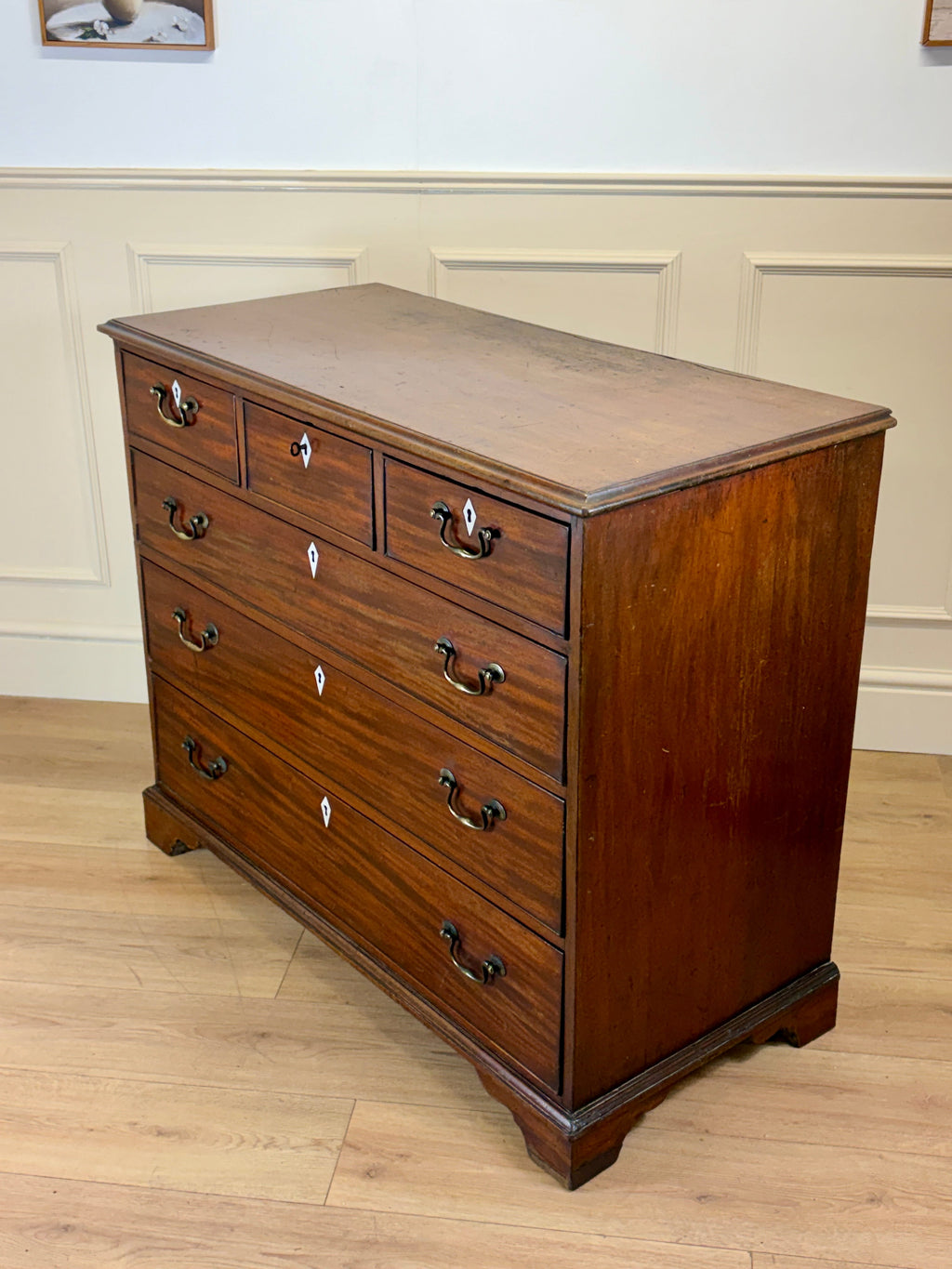 Wooden dresser with multiple drawers on a wooden floor.