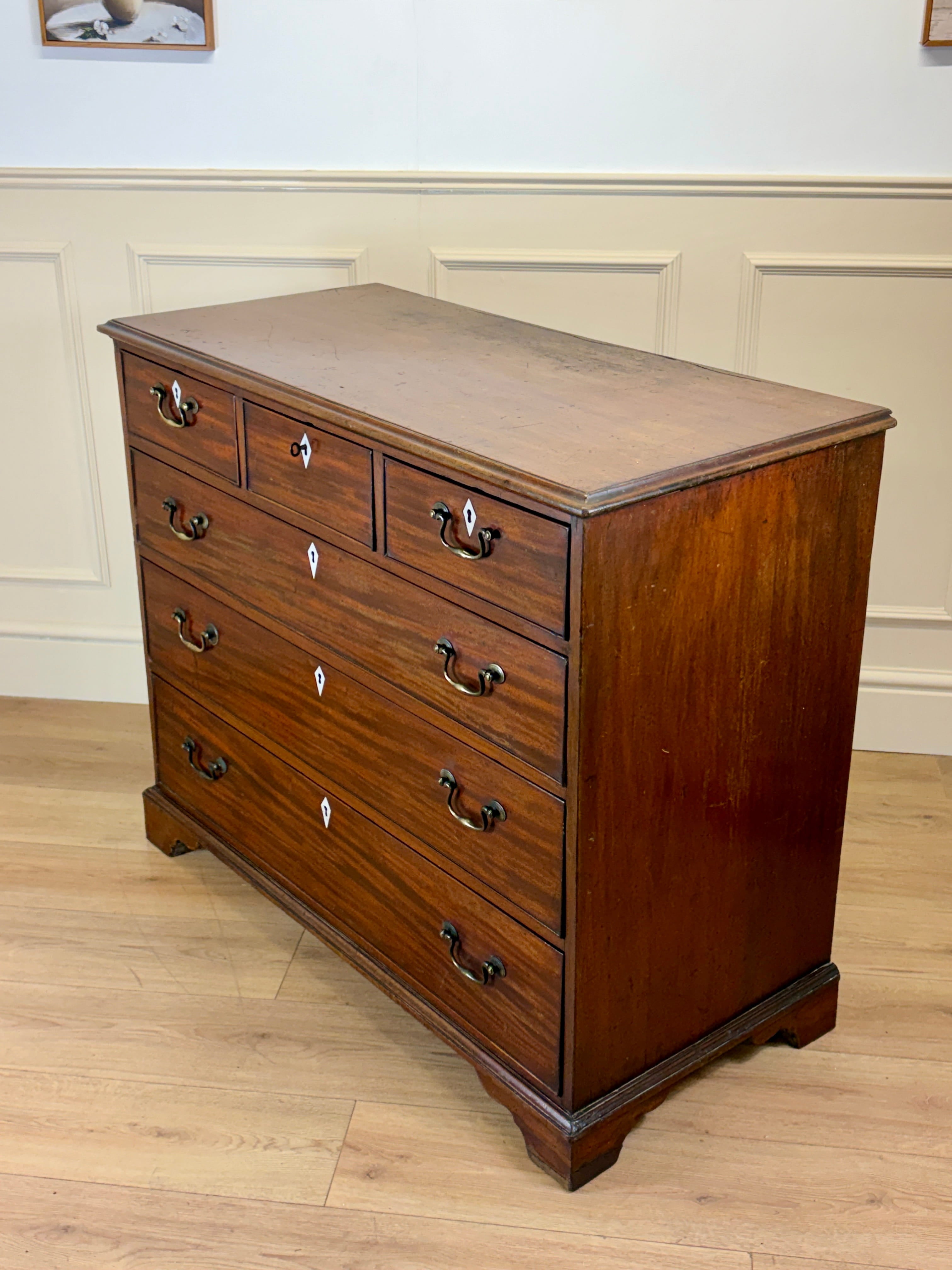 Wooden dresser with multiple drawers on a wooden floor.