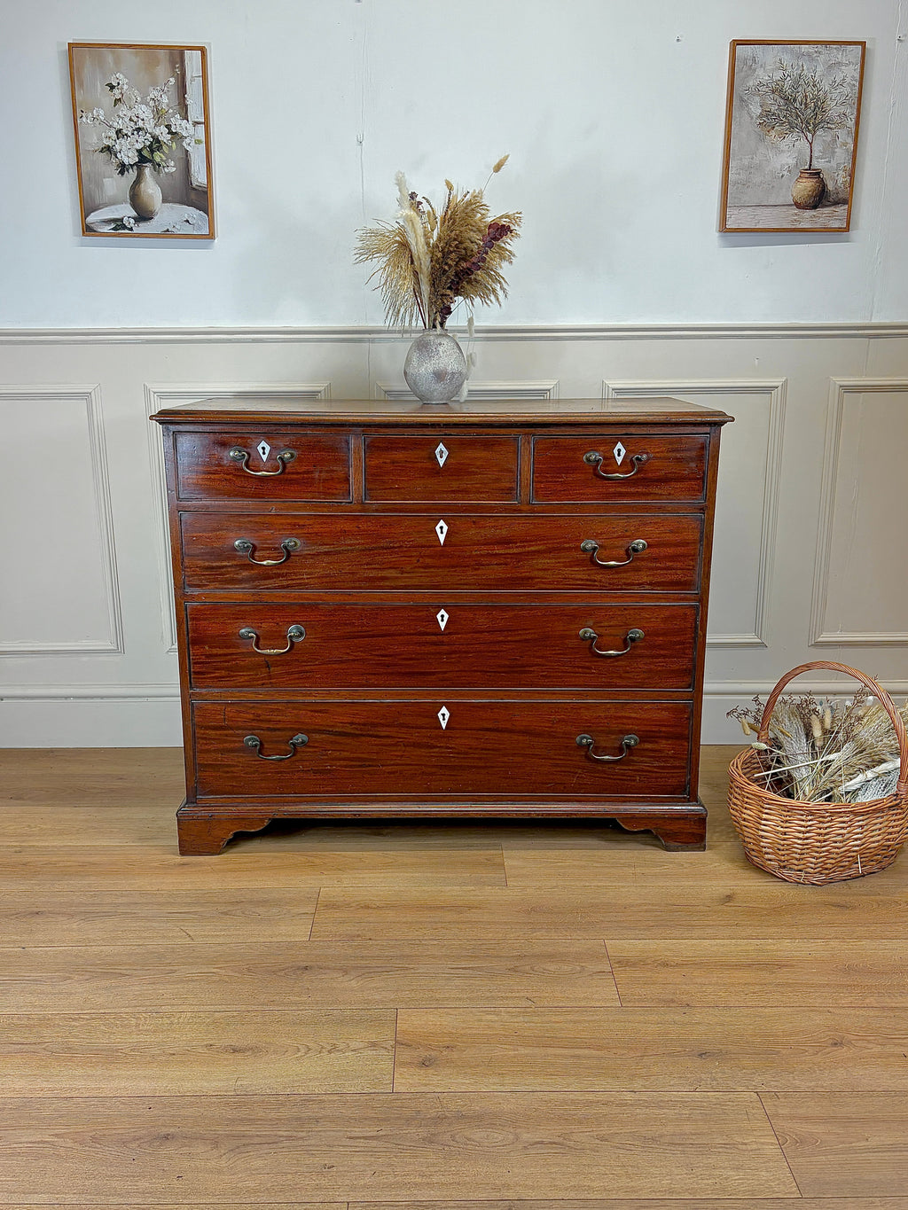 Wooden dresser with decorative items on a wooden floor and white walls.
