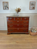 Wooden dresser with decorative items on a wooden floor and white walls.