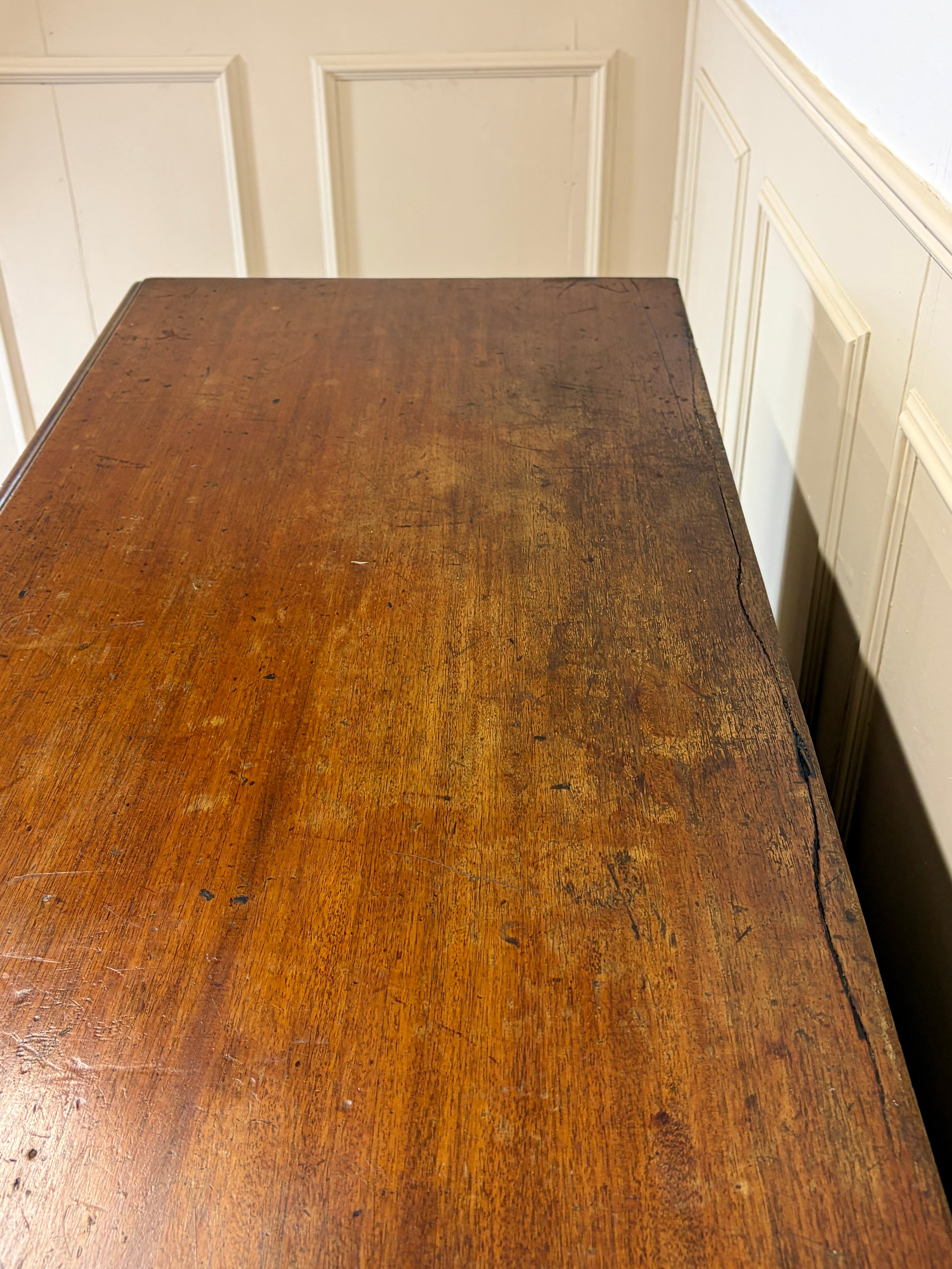 Old wooden table in a room with white paneled walls