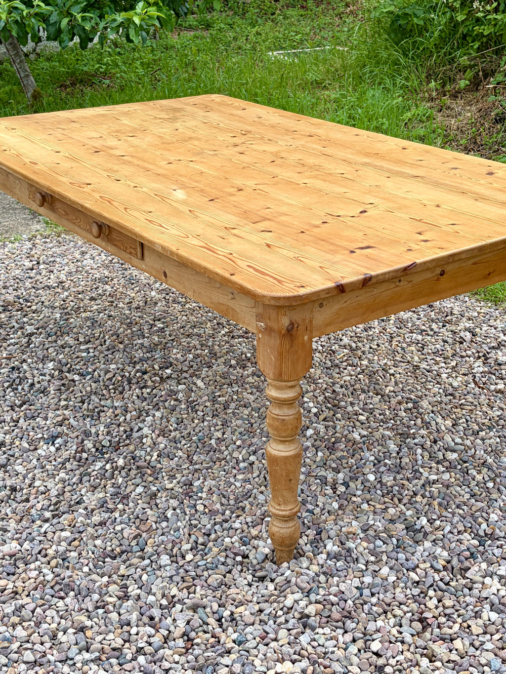 Wooden table on a gravel surface with grass in the background
