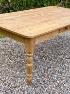 Wooden table with a single leg on a gravel surface