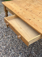 Wooden coffee table with an open drawer on a gravel surface
