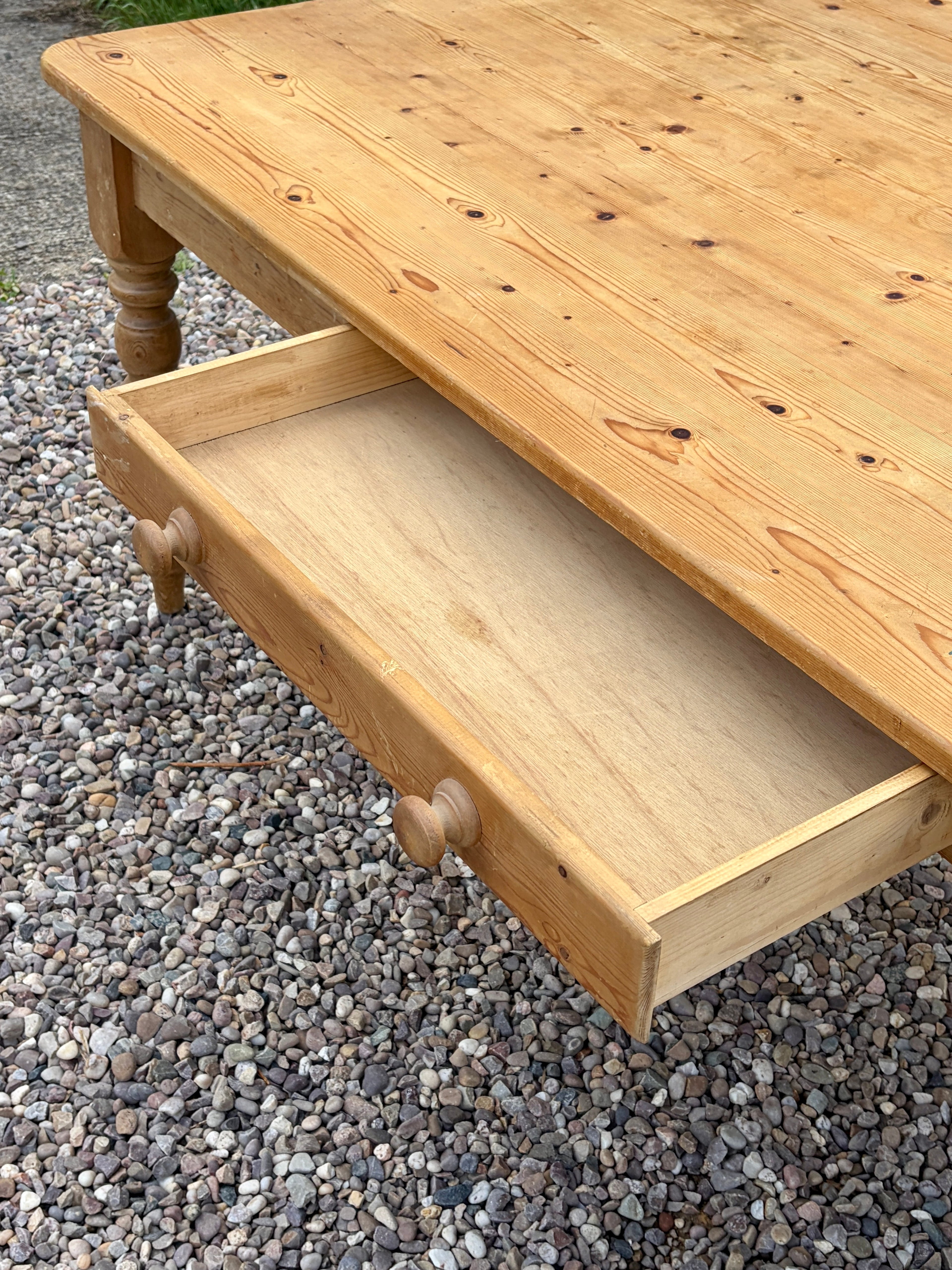 Wooden coffee table with an open drawer on a gravel surface