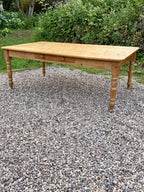 Wooden table on a gravel surface with greenery in the background