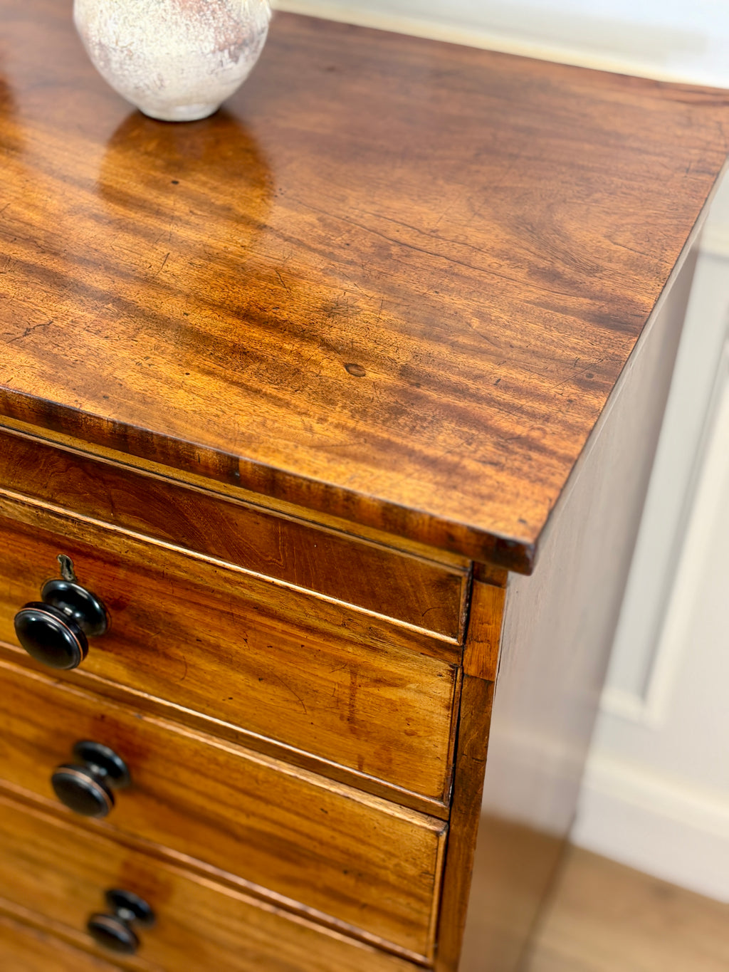 Wooden dresser with two drawers and a decorative item on top.
