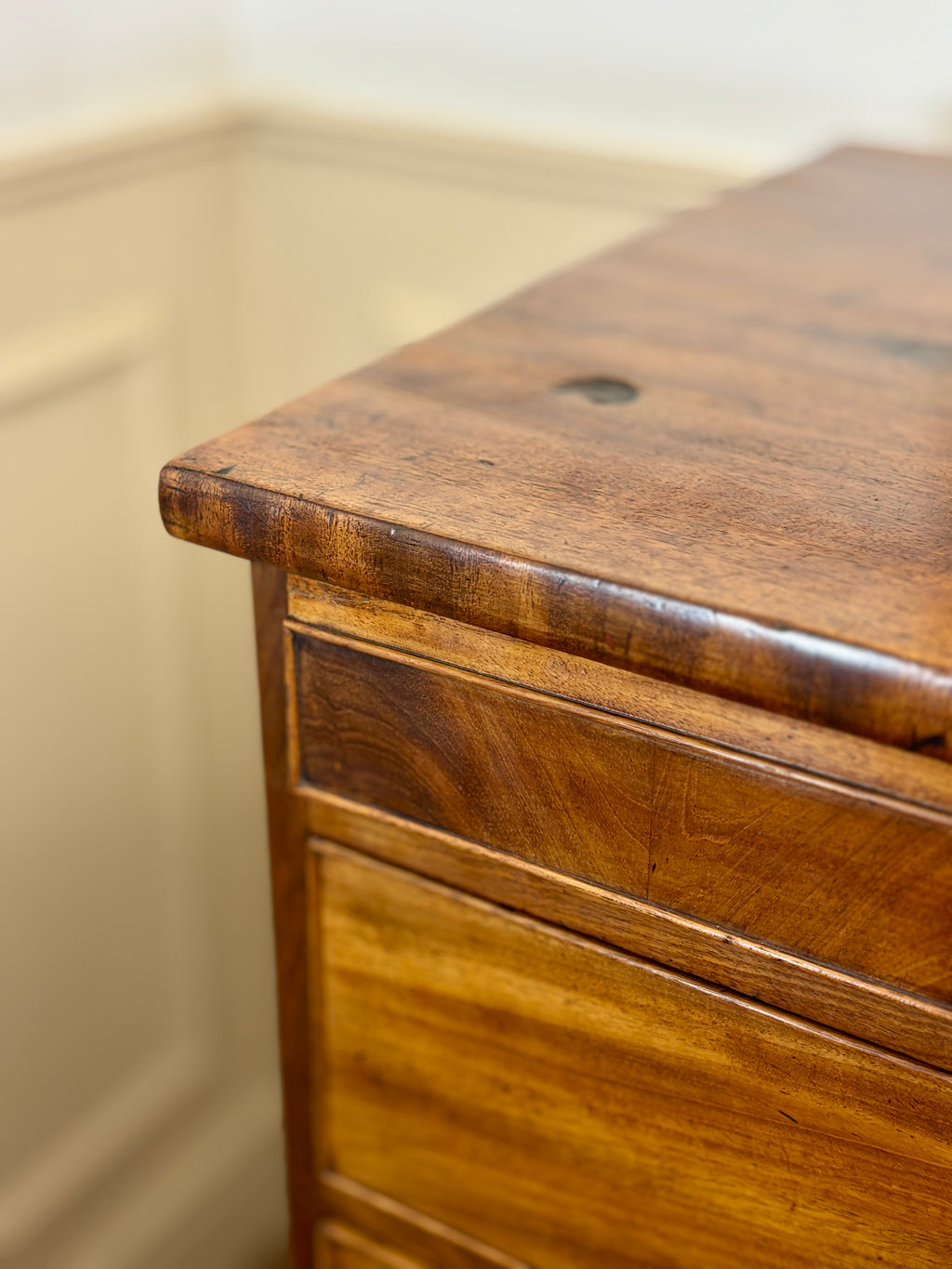 Close-up of a wooden drawer with a beige wall in the background