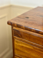 Close-up of a wooden drawer with a beige wall in the background