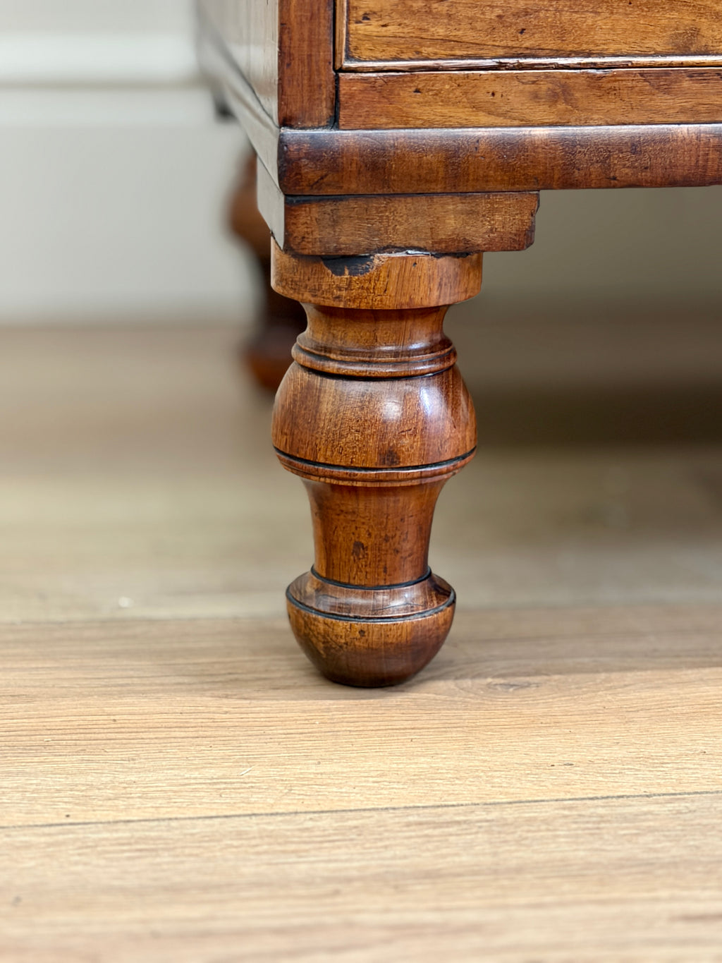 Close-up of a wooden leg on a piece of furniture with a neutral background