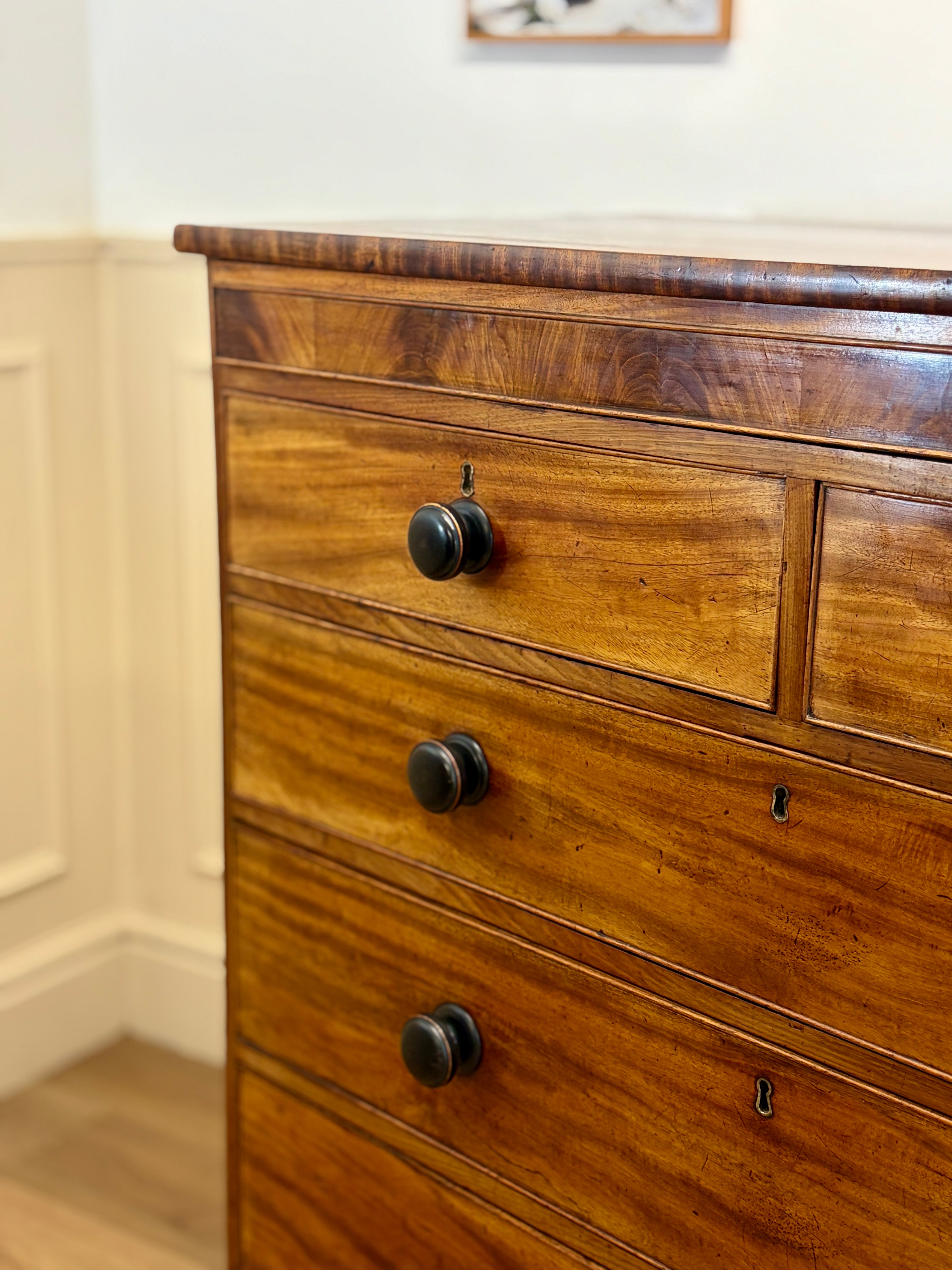 Wooden dresser with three drawers and black handles in a room setting.