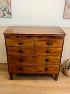 Wooden dresser with four drawers on a wooden floor.