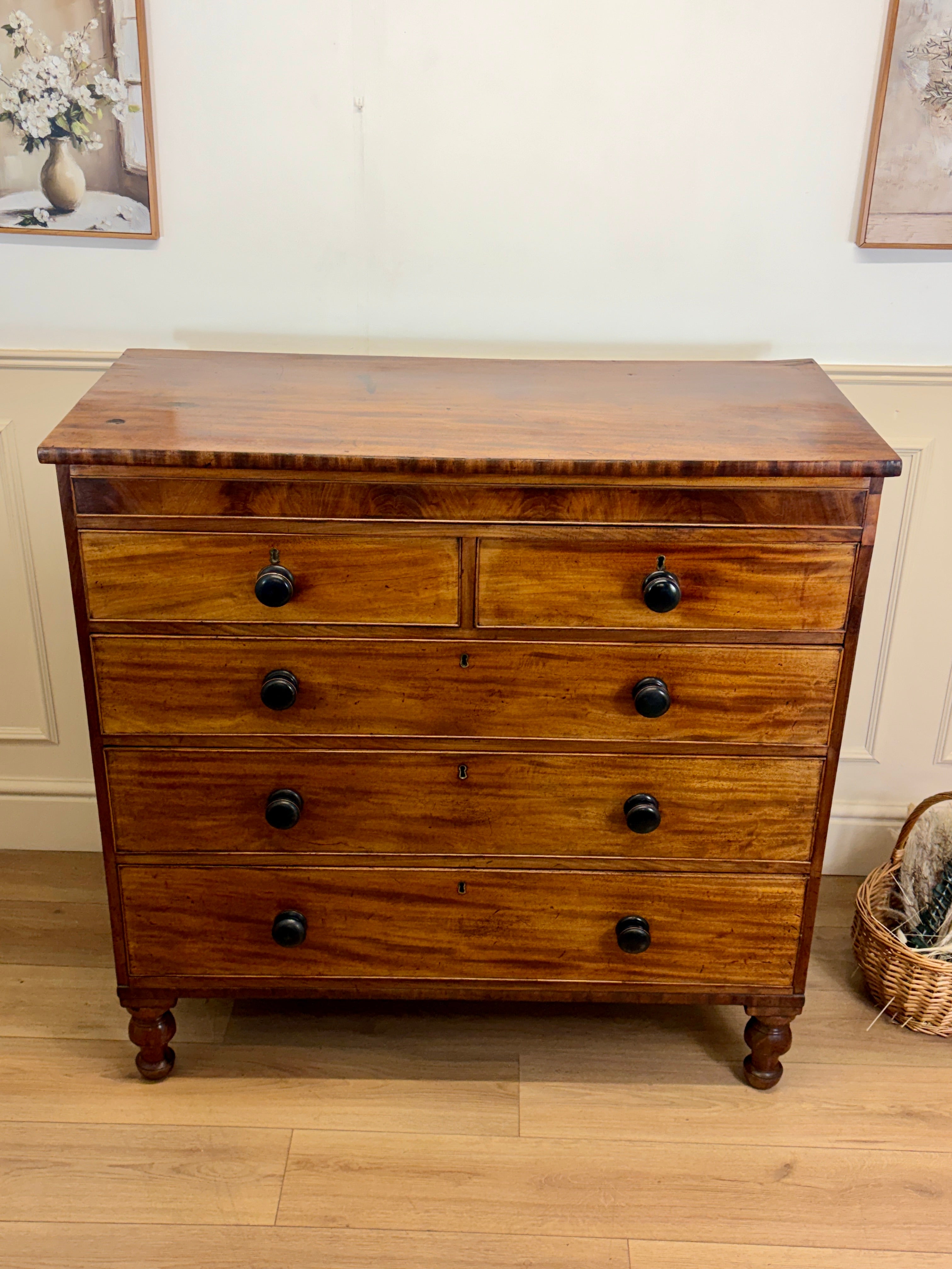 Wooden dresser with four drawers on a wooden floor.