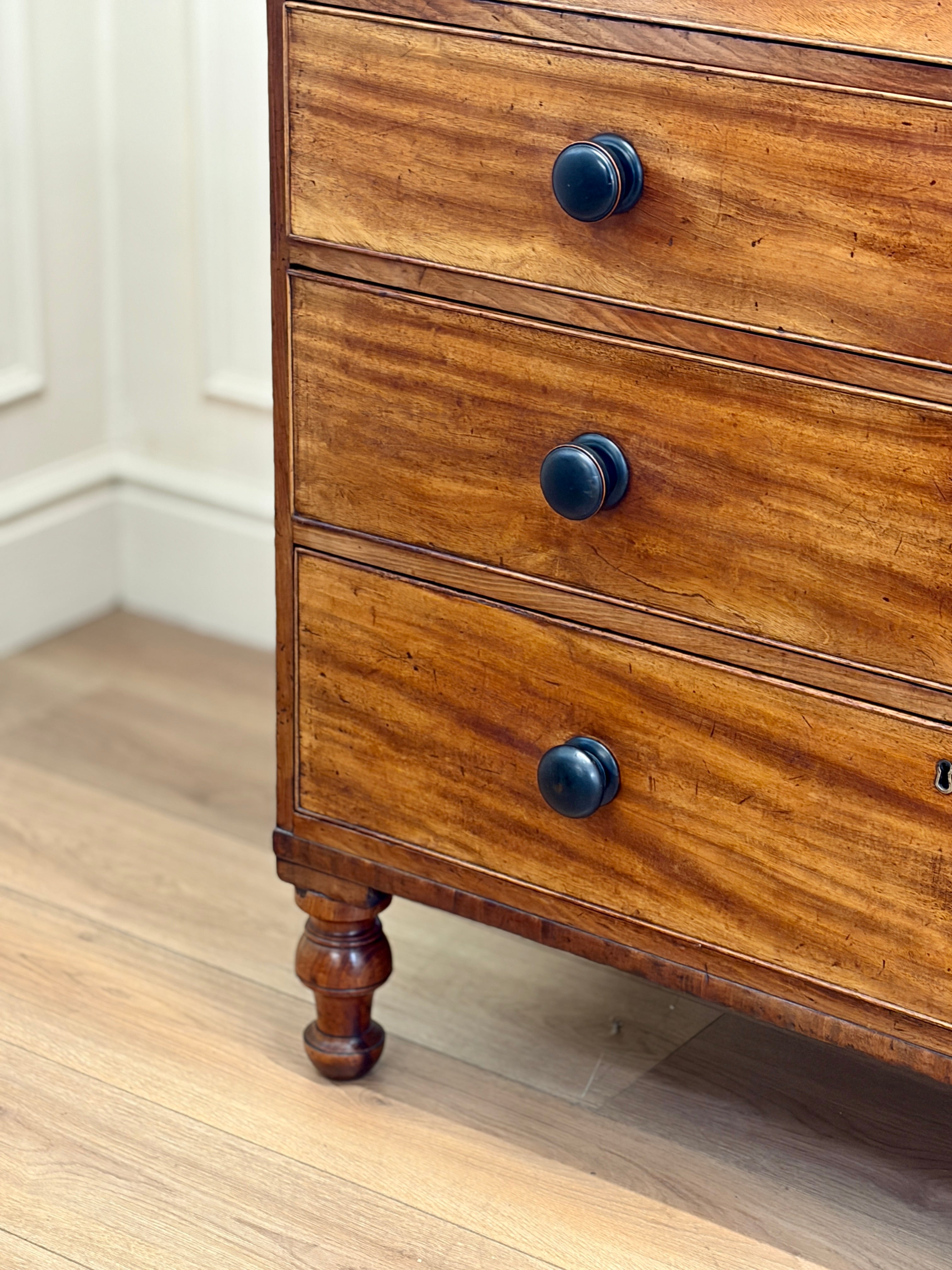 Wooden dresser with three drawers on a wooden floor.