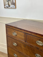 Wooden dresser with brass handles against a white wall